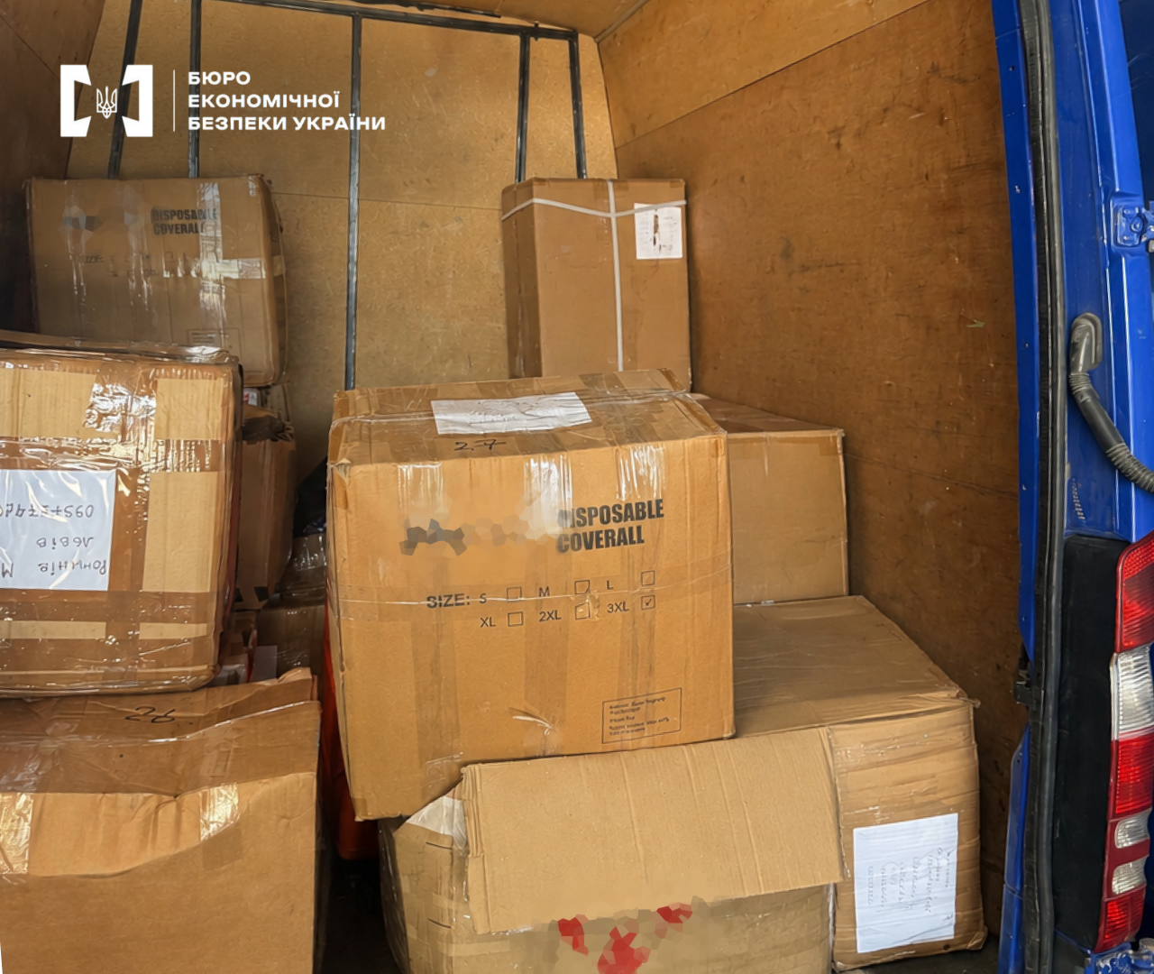 A cargo compartment of a blue van filled with cardboard boxes containing illegal goods.