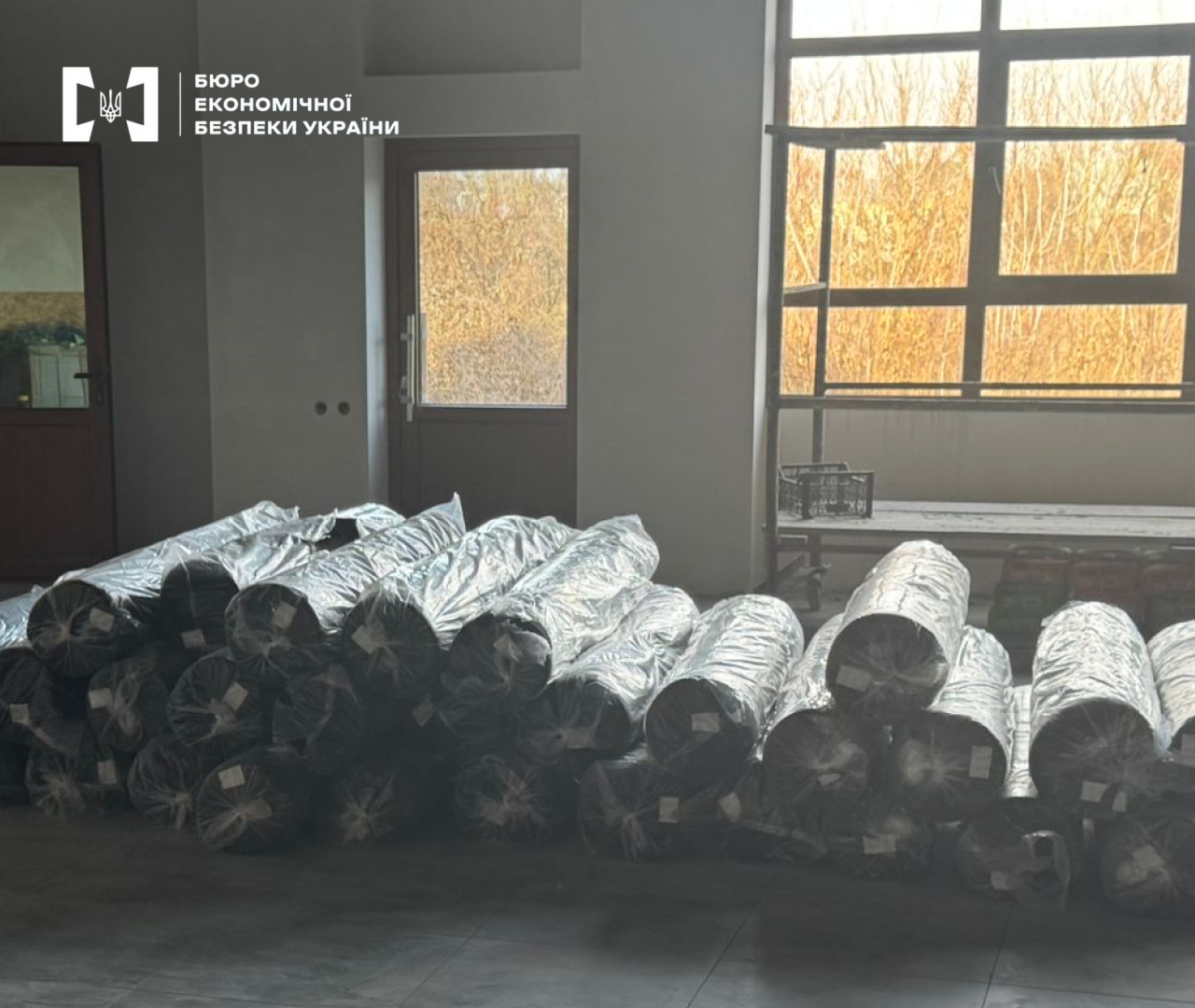 Rolls of black woollen cloth and knitwear stacked on the workshop floor.