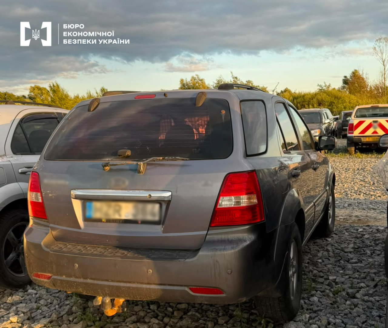 A grey Kia crossover with European registration plates at an impound lot.