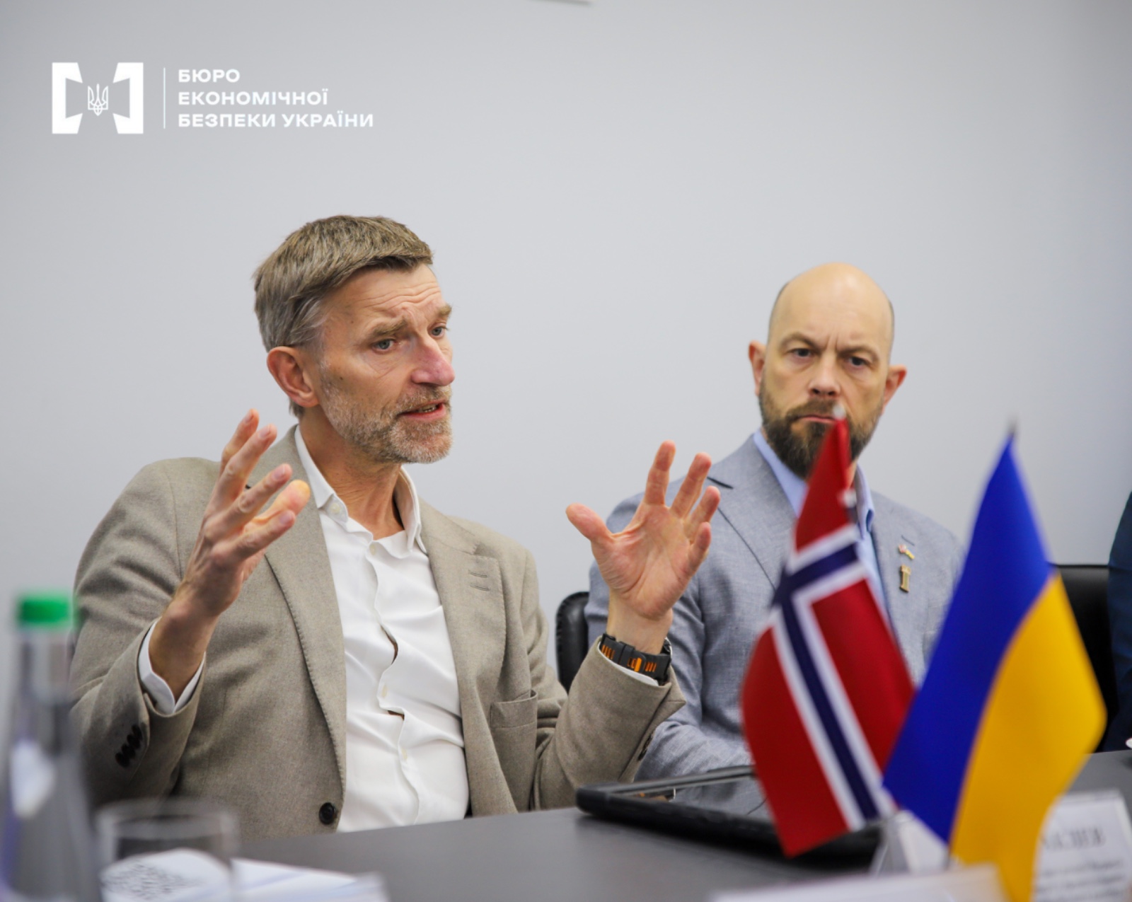 Representatives of Norway at a table during a meeting. There are small flags of Norway and Ukraine on the table