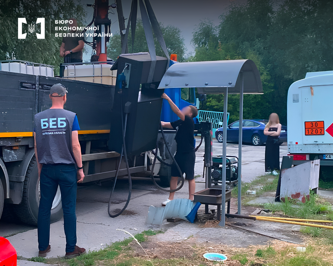 A ESBU detective oversees the dismantling of an illegal fuel dispenser using a crane manipulator.