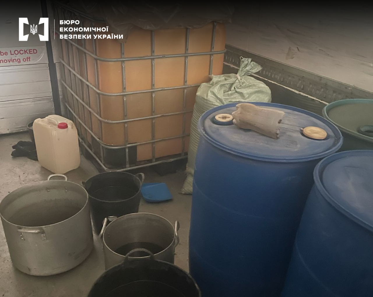 Industrial containers discovered by law enforcement officers: blue drums, metal buckets, and an IBC tote in the cargo compartment of a vehicle