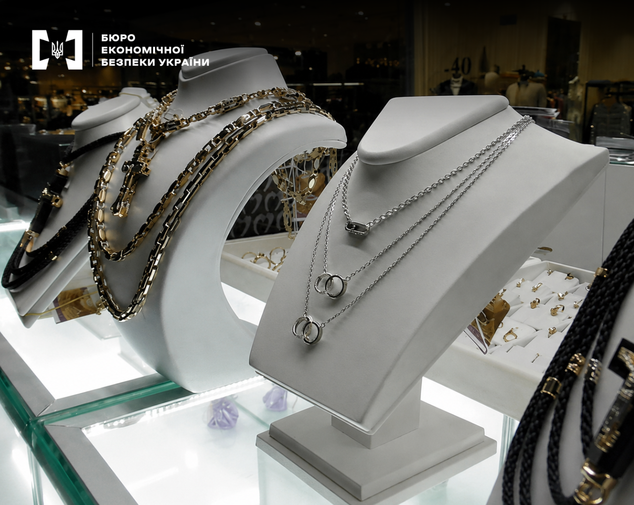Jewelry, chains, and pendants on white stands in a shop window display.