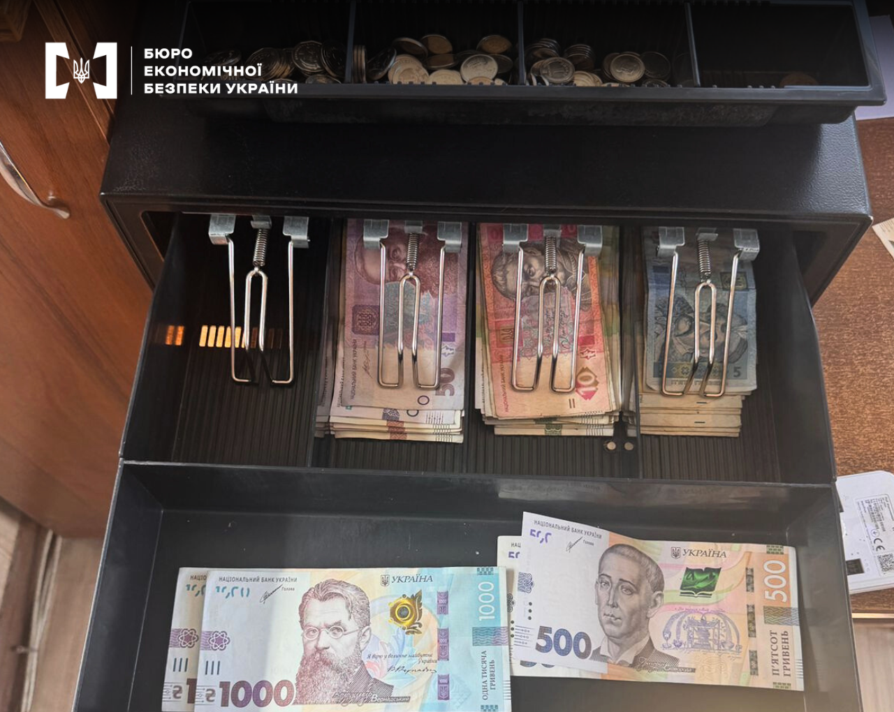An open cash drawer with paper hryvnias and coins
