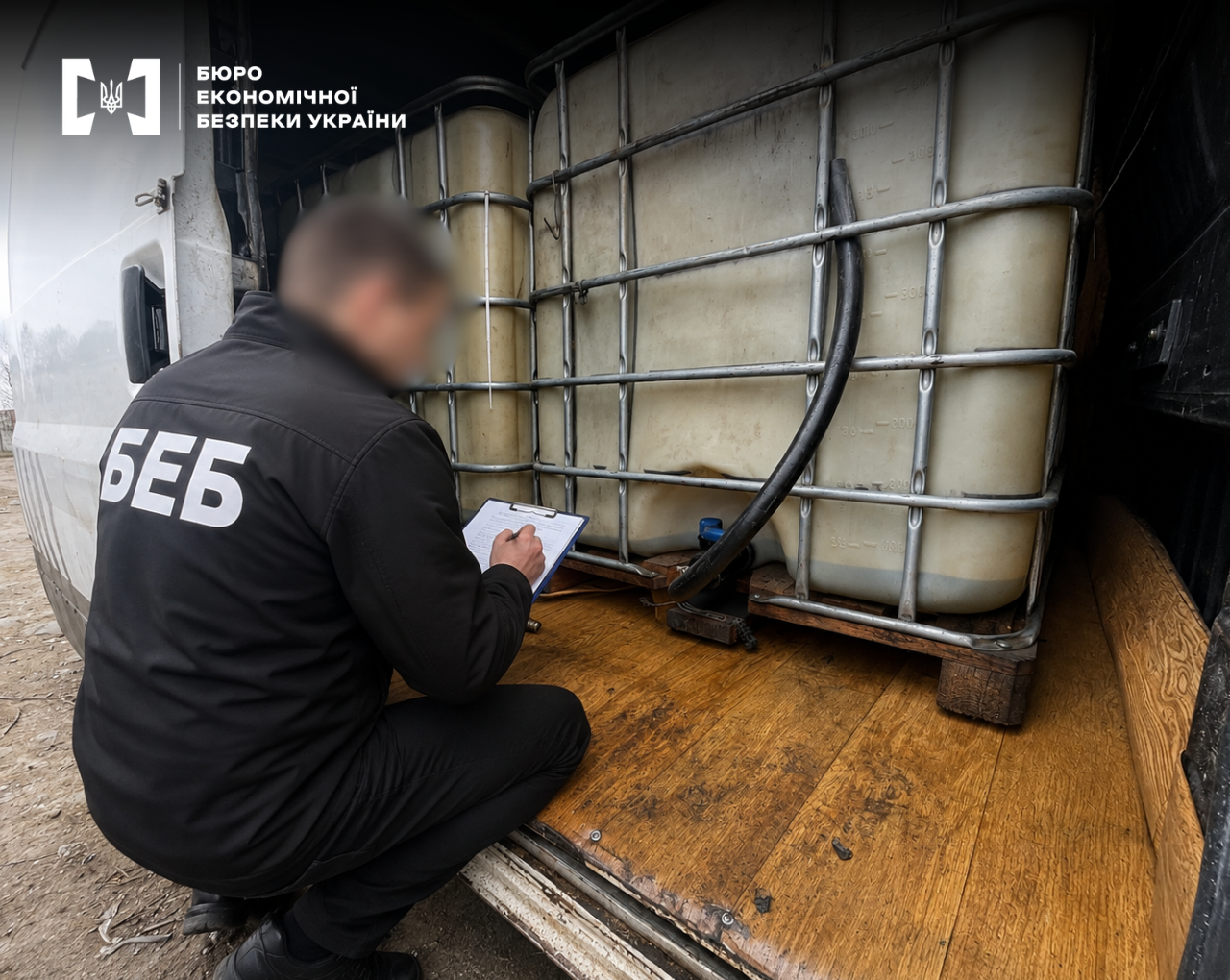 A ESBU detective logs evidence next to large white intermediate bulk containers in a metal cage on a wooden pallet.