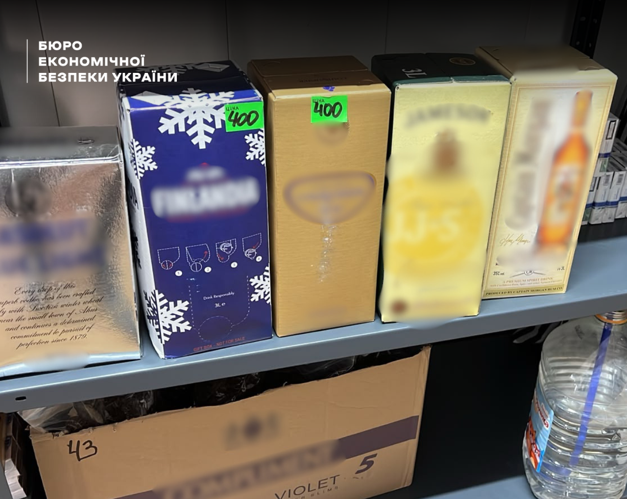 In a warehouse premises, boxes of Finlandia vodka, Jameson whiskey, and Captain Morgan rum stand on shelves with blurred logos.