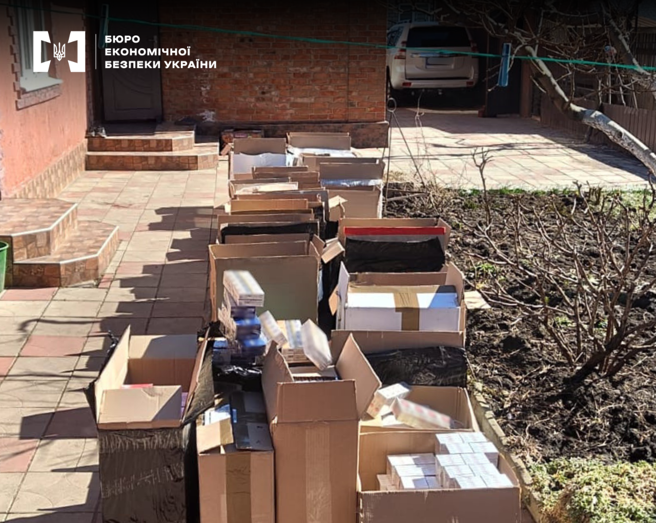 A long row of cardboard boxes containing contraband cigarettes in the courtyard of a house.