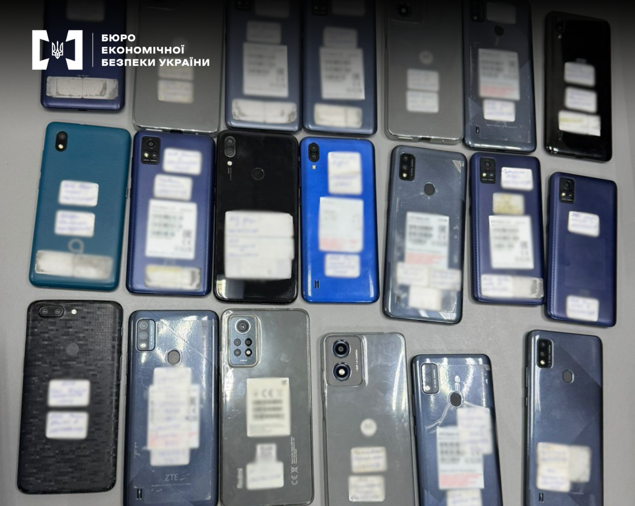 Dozens of mobile phones of different brands, models, colors and sizes are neatly arranged on a large table