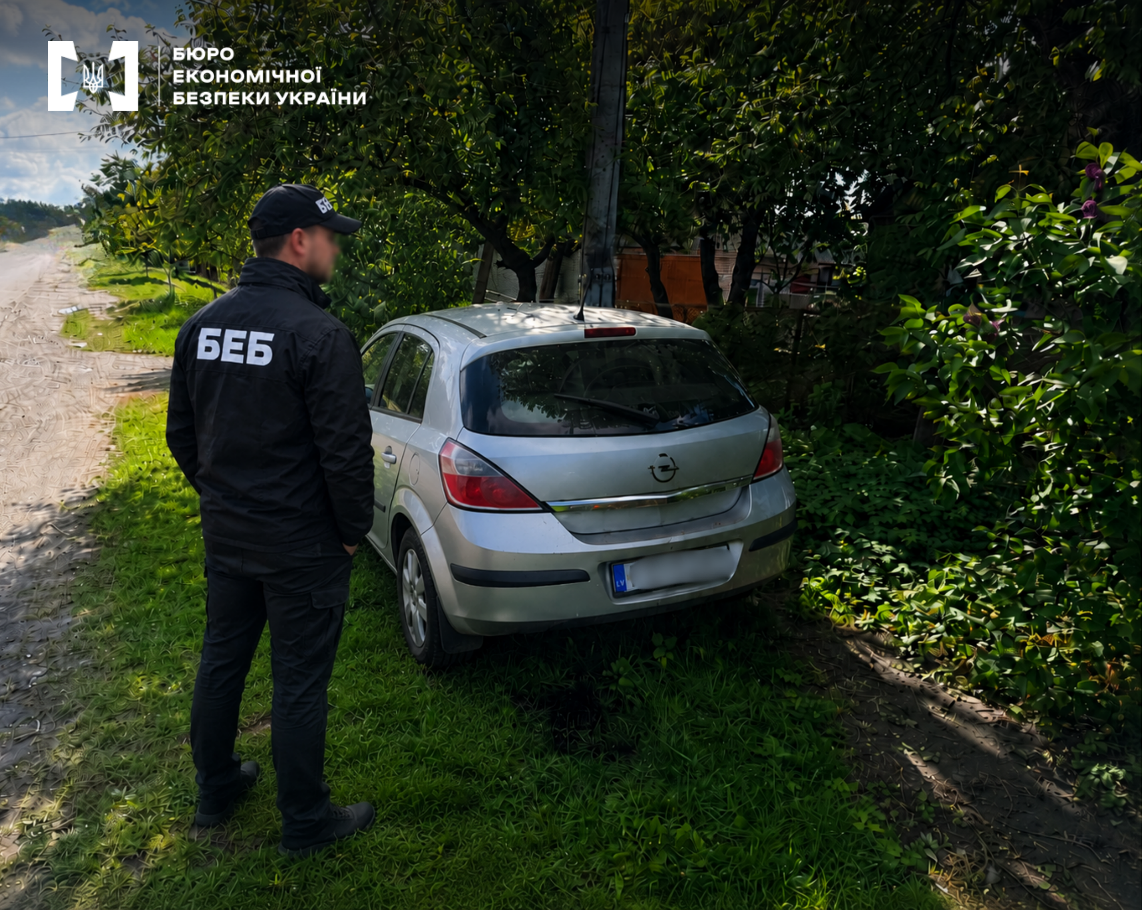 A ESBU detective next to a silver Opel Astra during investigative activities on the road