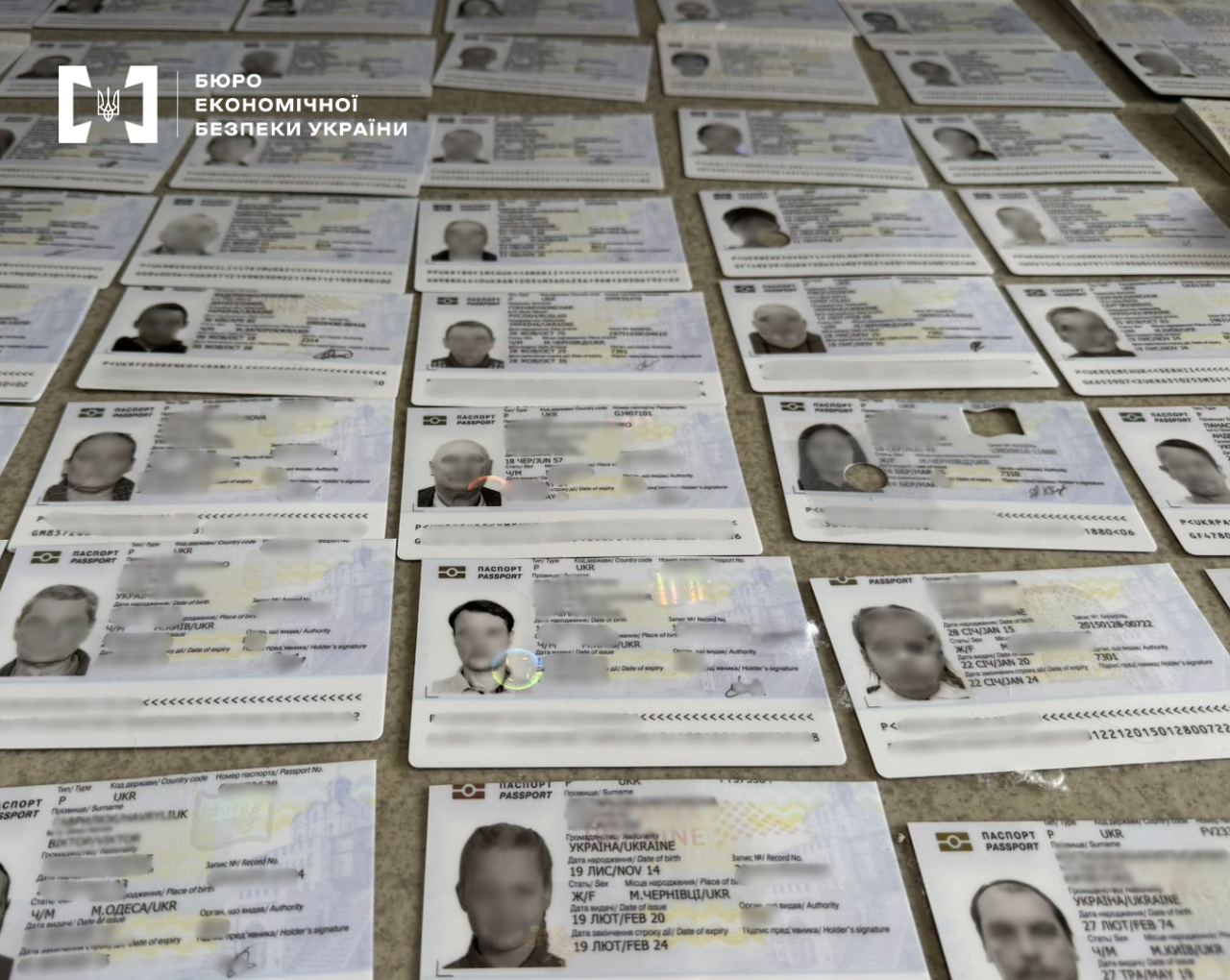 A large number of Ukrainian international passports laid out, with personal data redacted.