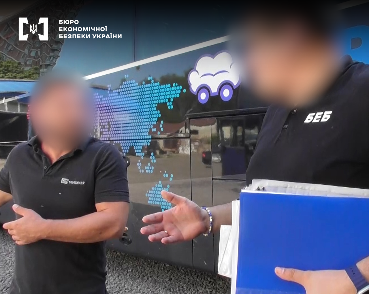 An ESBU detective speaking with a man in a DB Schenker t-shirt against the background of a branded truck. Faces are hidden