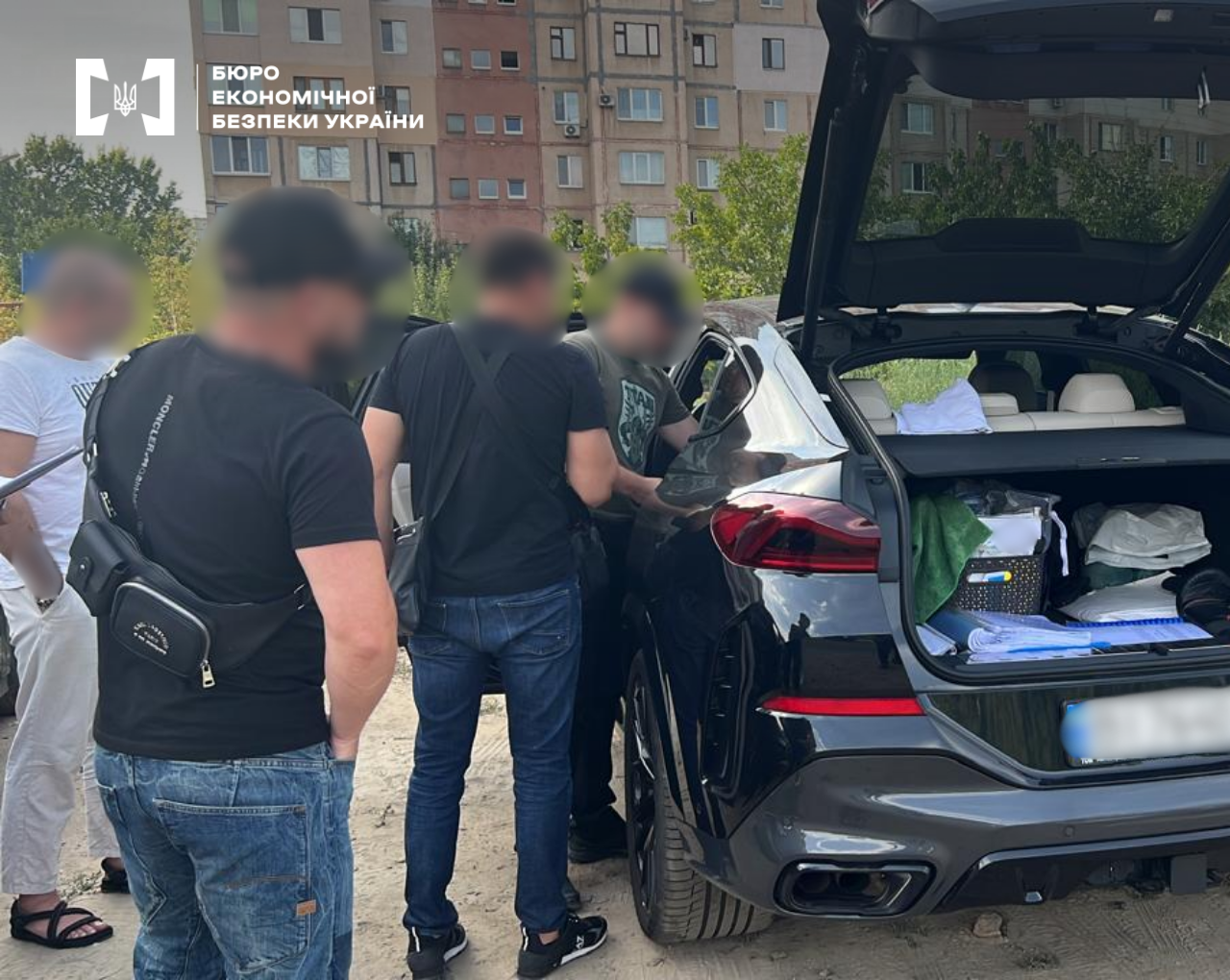ESBU investigative actions on the street near the vehicle of the suspects in the case. The faces of the men and the car plates are blurred.