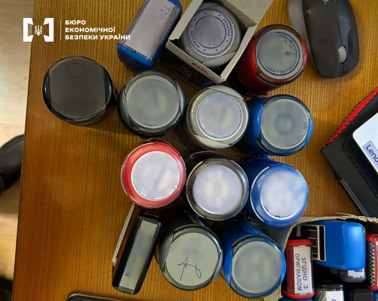 A large cluster of round and rectangular seals of various firms on a wooden table.