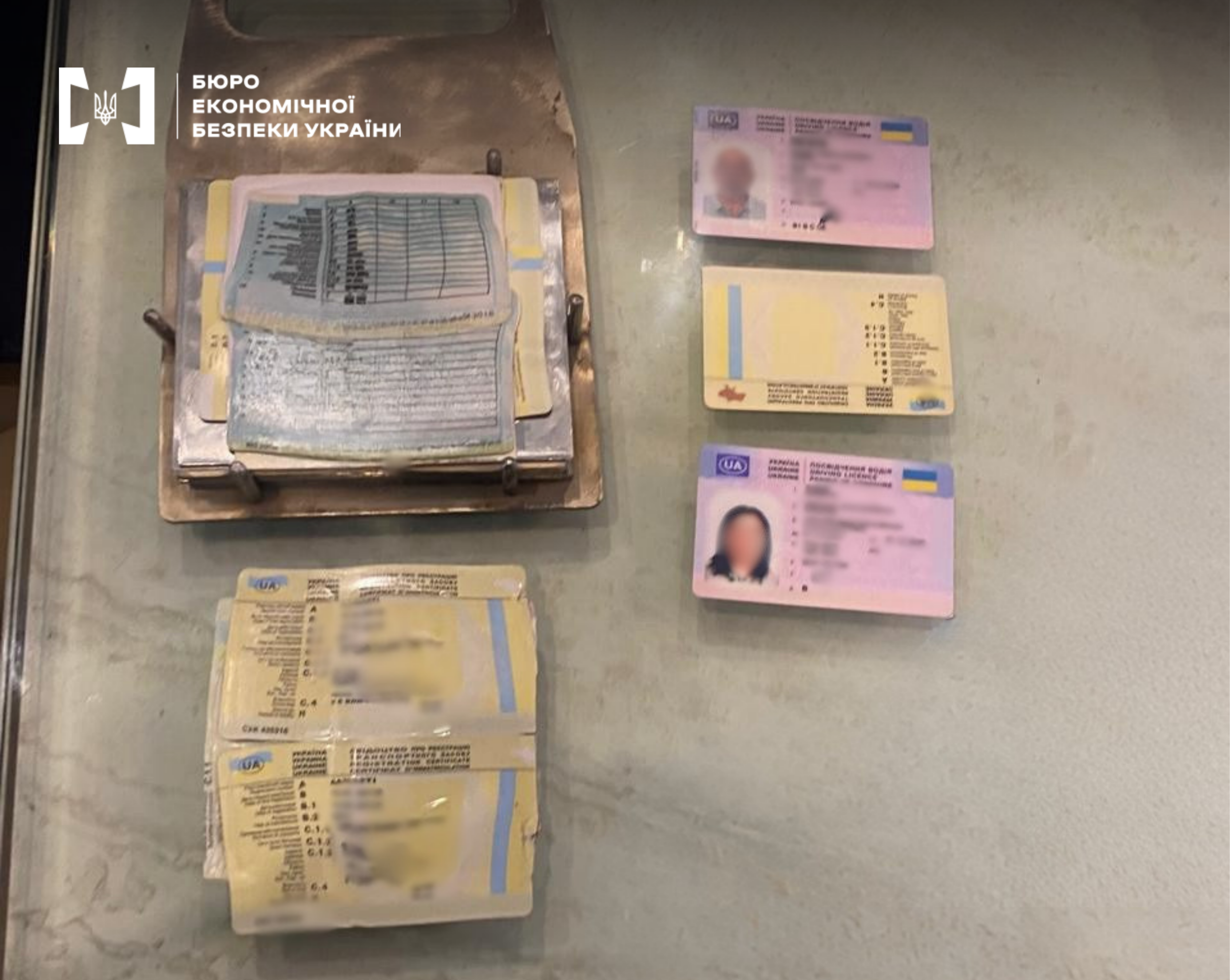 Plastic driver's license cards and paper registration certificates on a table. A press mold is also visible.