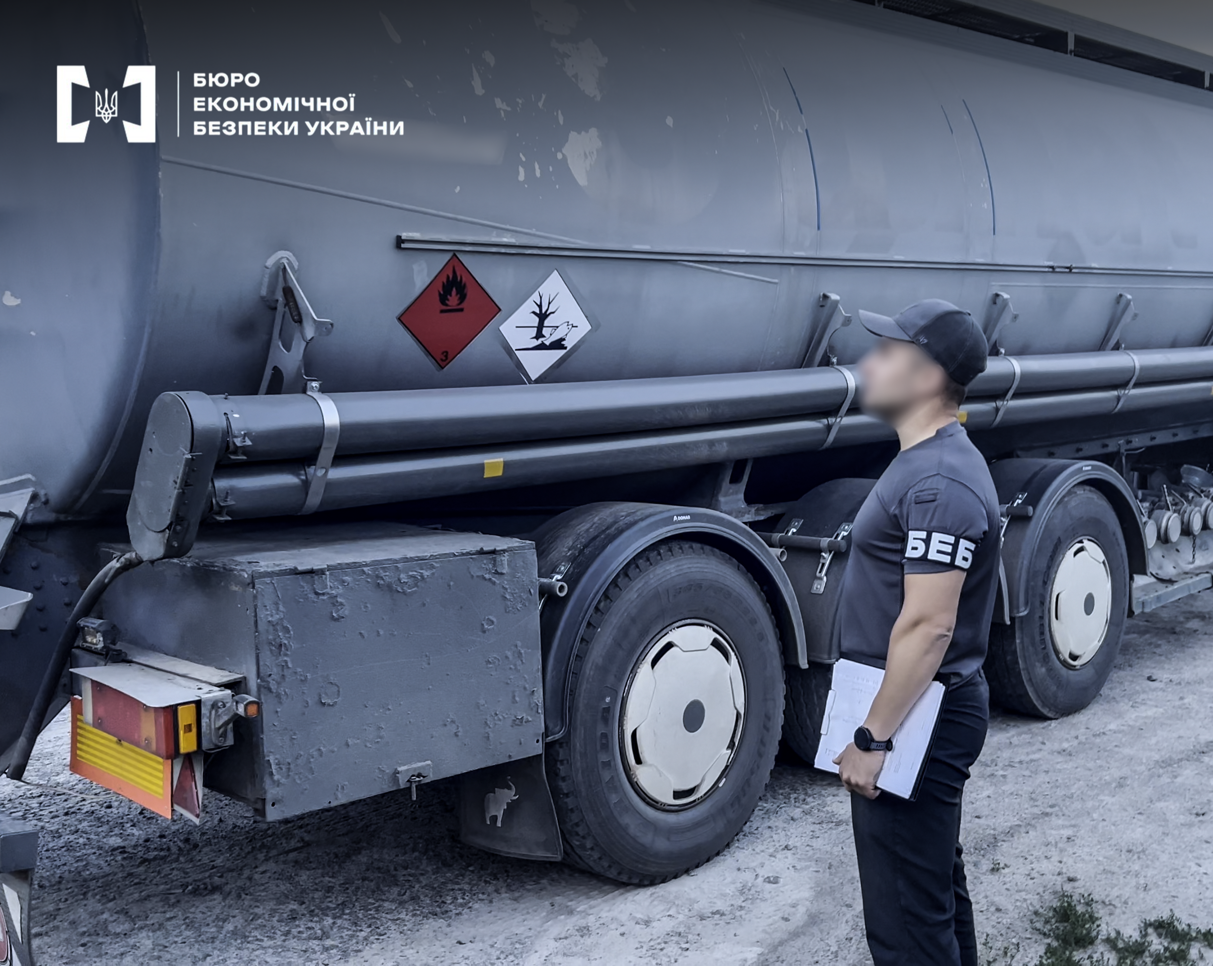 A ESBU detective with documents inspects a fuel tanker truck marked for hazardous cargo.