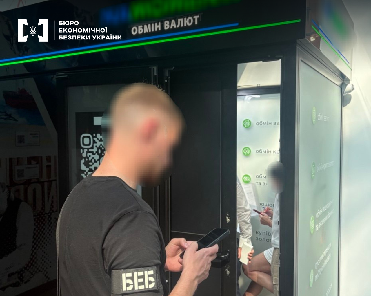 Investigative actions of the ESBU near a currency exchange kiosk, with another employee visible inside the premises holding documents