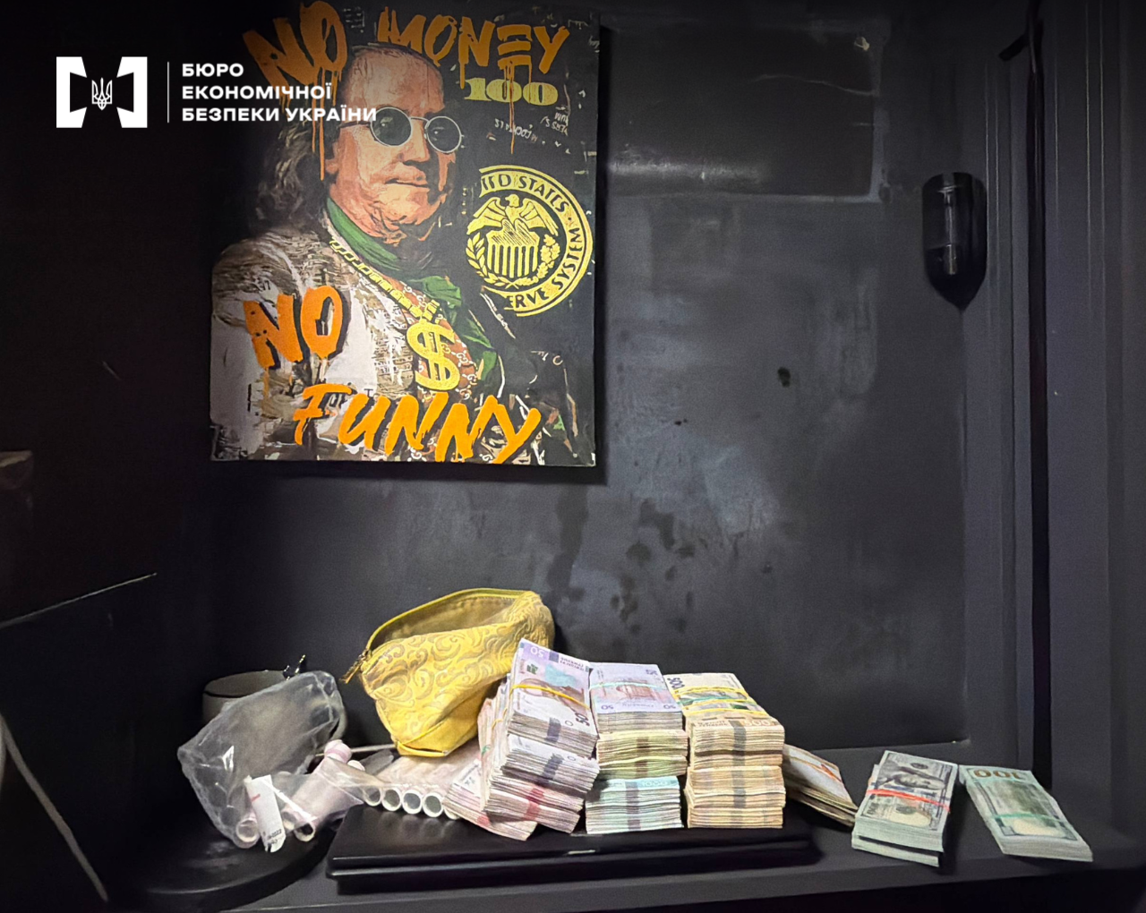Large stacks of seized euro and dollar banknotes against the background of a bold painting featuring Benjamin Franklin and the inscriptions "NO MONEY NO FUNNY".