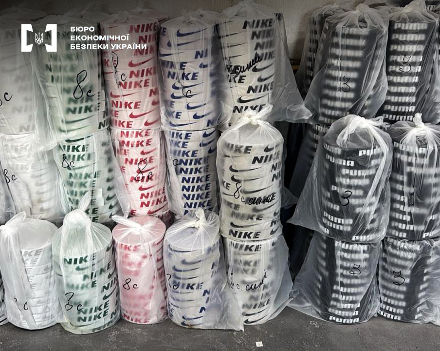 Stacks of counterfeit sports shoes with Nike and Puma logos in transparent bags.
