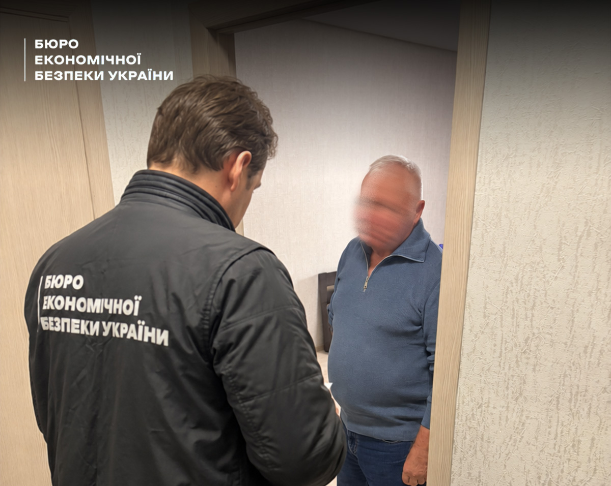 A ESBU detective with their back to the camera stands in a doorway opposite an elderly man in a blue sweater.