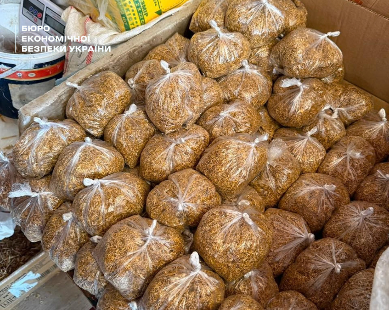 Yellow-brown tobacco packaged in plastic sacks, stacked in large cardboard boxes.