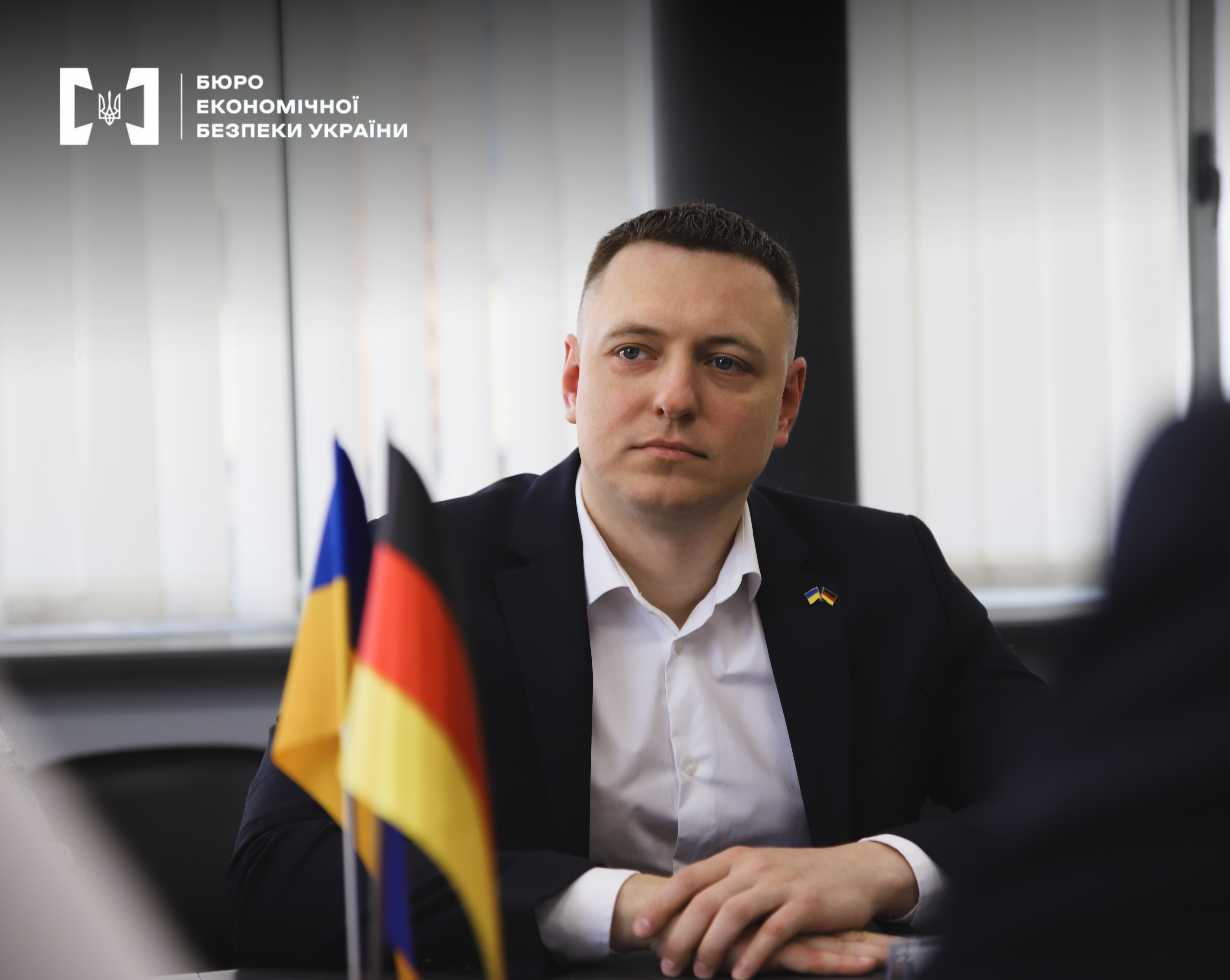 The Deputy Head of the ESBU at the negotiating table against the background of the table flags of Ukraine and Germany.