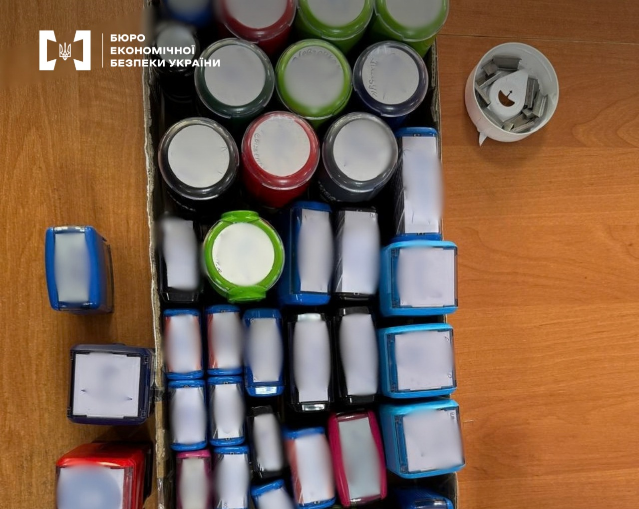Rows of multi-colored round and rectangular stamps on a wooden desk next to an ink pad.