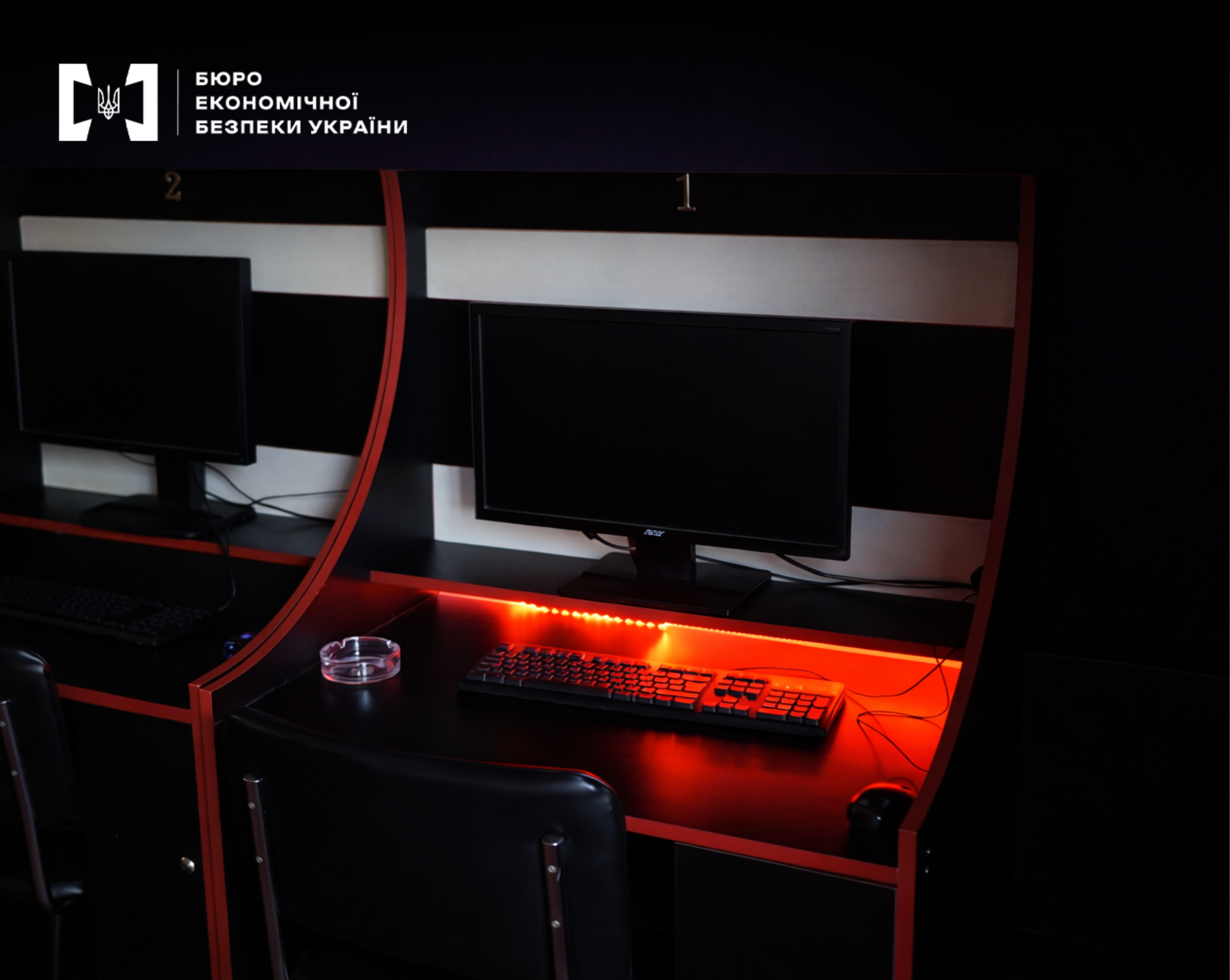 A computer workstation with red LED lighting and an ashtray in an exposed underground gambling hall.
