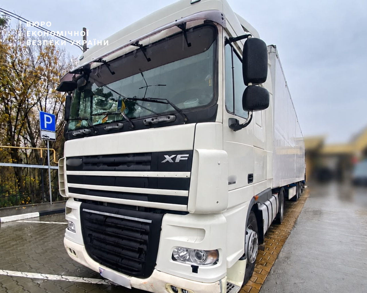 A white DAF XF cargo truck with a semi-trailer in a parking lot.