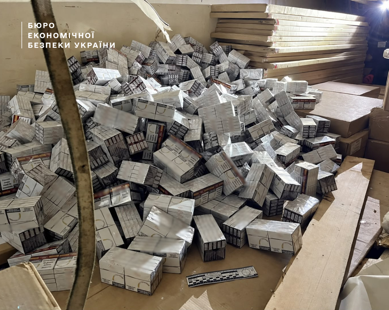 A large pile of cigarette packs without excise tax stamps in a warehouse during a search.