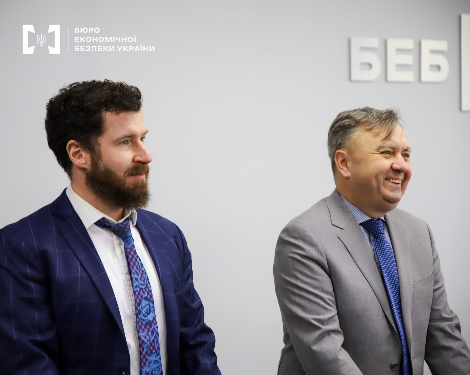 Two men in business suits against a light background