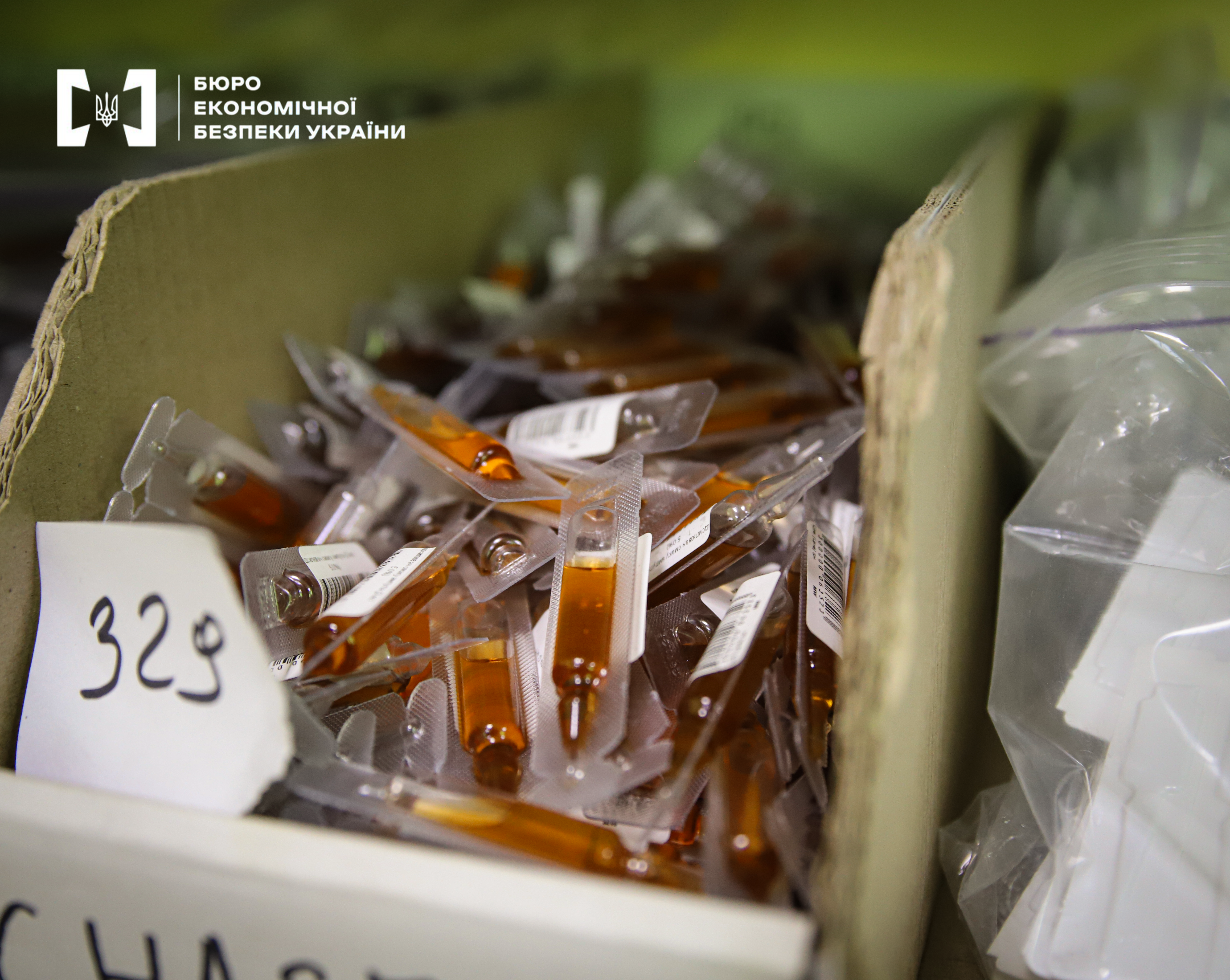 A large quantity of glass ampoules containing a brown liquid. Each ampoule is individually packaged in plastic and labeled. A piece of paper with the number '329' is placed on top
