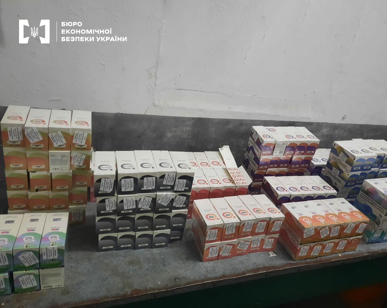 Складені на підлозі вилучені коробки з електронними сигаретами різних смаків та дизайнів.